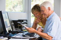 Senior couple using wireless IT equipment in home office